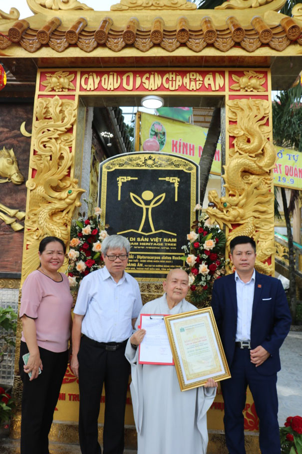 A group of people standing in front of a gold archDescription automatically generated