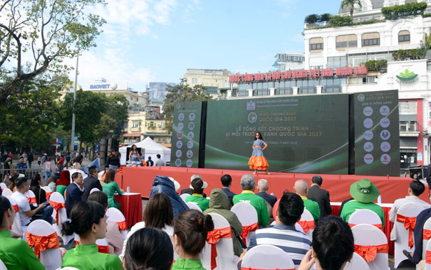 A person standing on a stage with a crowd watchingDescription automatically generated