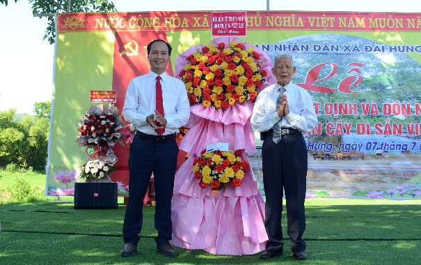 Two men standing in front of a signDescription automatically generated