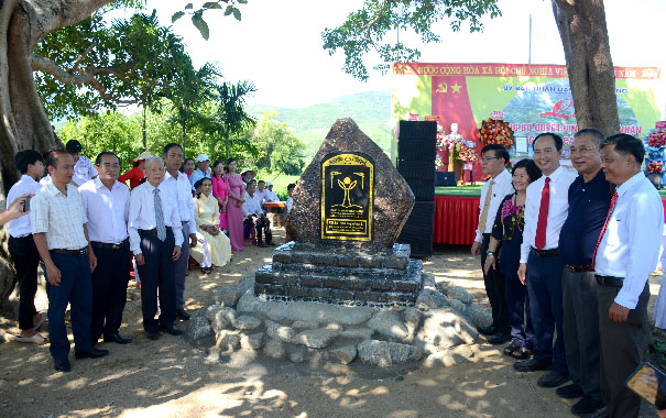 A group of people standing around a stone monumentDescription automatically generated