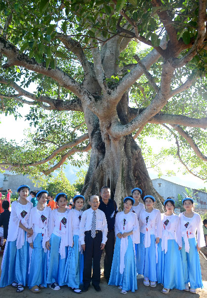 A group of people standing in front of a large treeDescription automatically generated