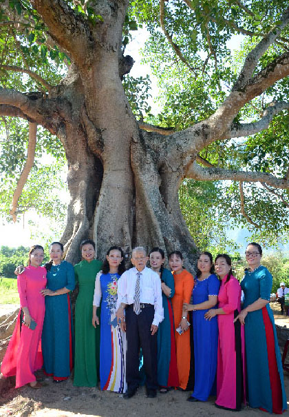 A group of people standing under a treeDescription automatically generated