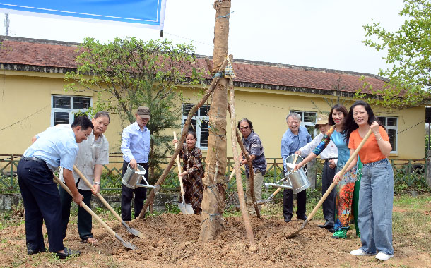 A group of people planting a treeDescription automatically generated