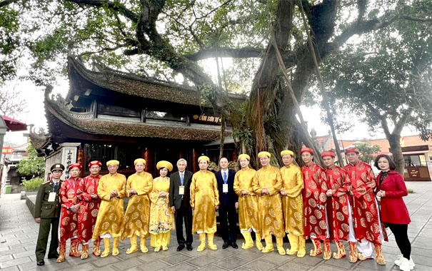 A group of people in traditional attire standing in front of a treeDescription automatically generated