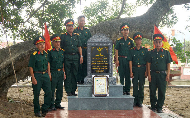 A group of people in uniform standing in front of a plaqueDescription automatically generated