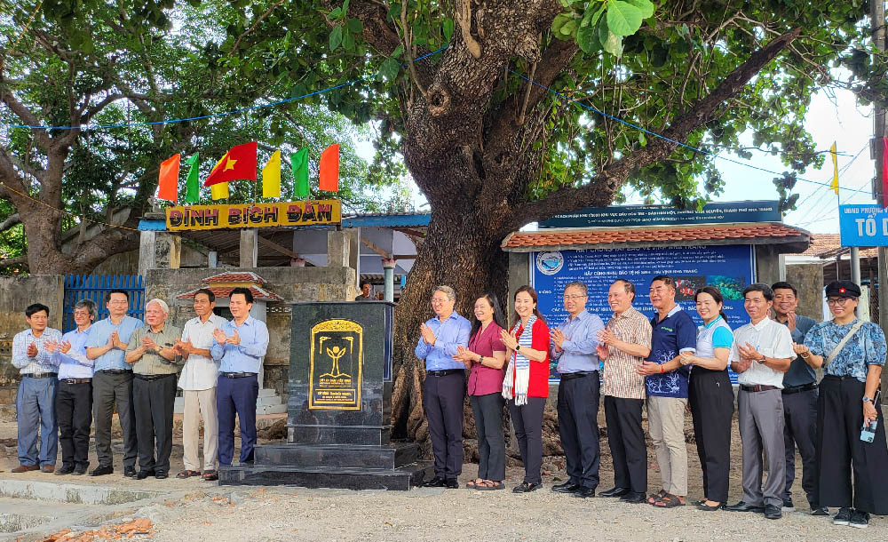 A group of people standing in front of a treeDescription automatically generated