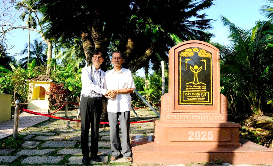 Men standing next to a stone monumentDescription automatically generated