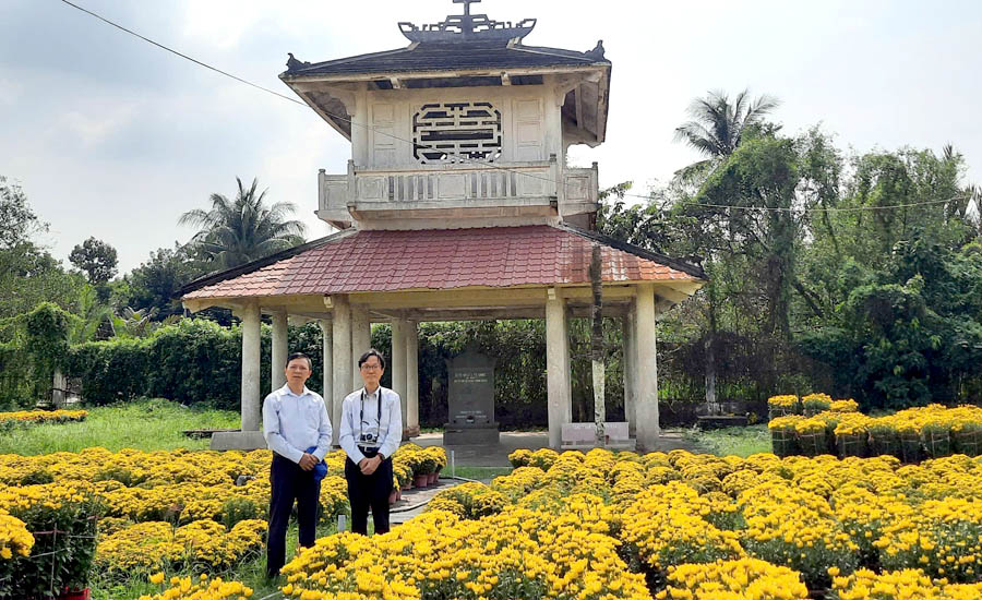 Two men standing in front of a flower gardenDescription automatically generated