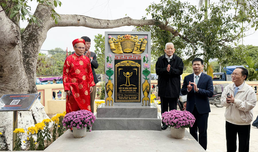 A group of people standing next to a stone monumentDescription automatically generated